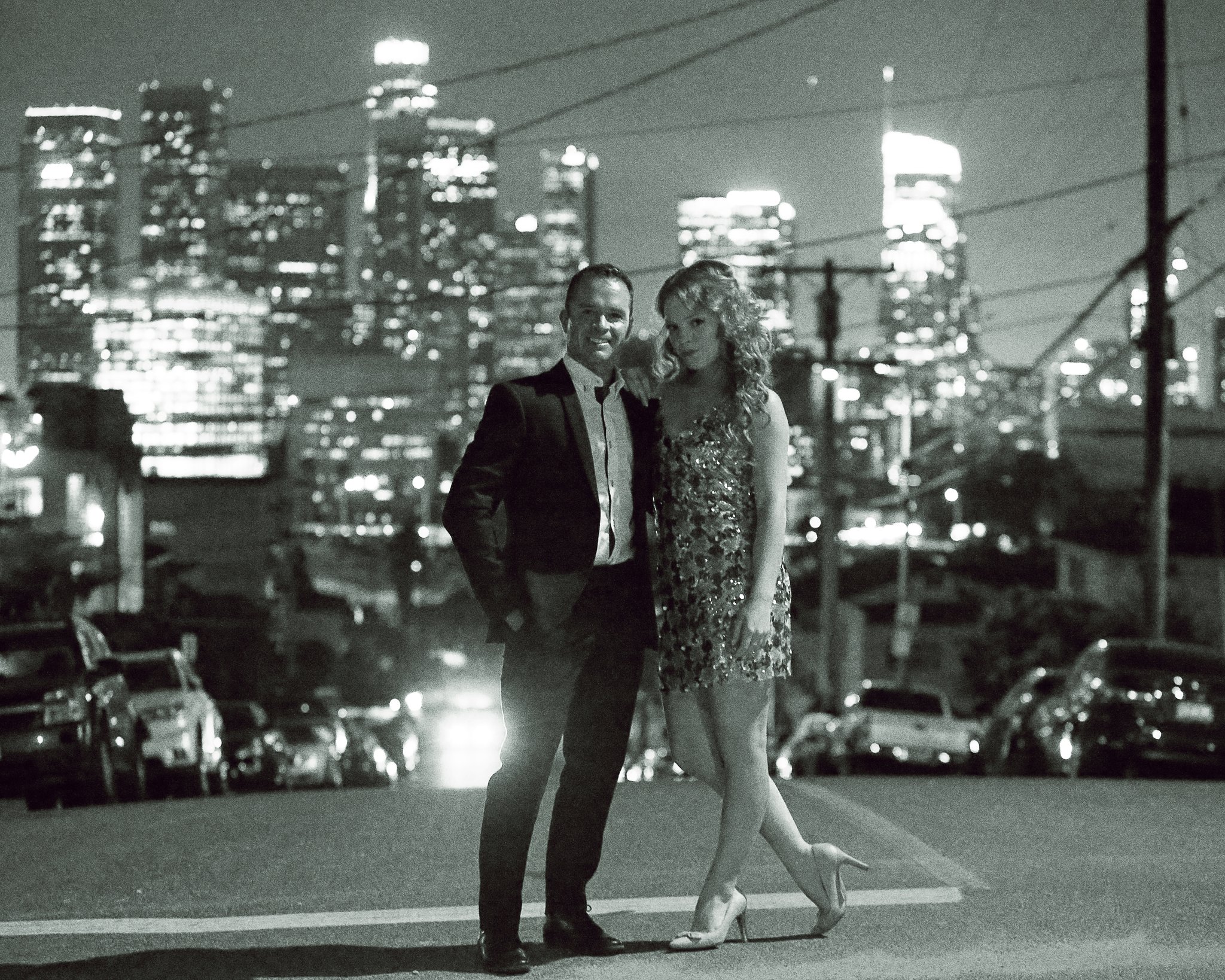 McKay Stewart in a tuxedo with Tea McKay on a Los Angeles street at night, downtown skyline behind them, black and white