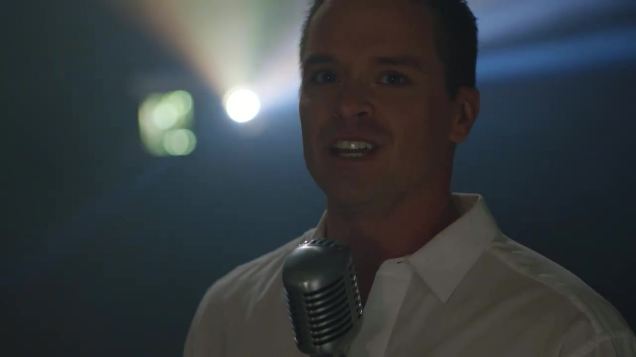 McKay Stewart singing into a vintage microphone in the Never Stop music video