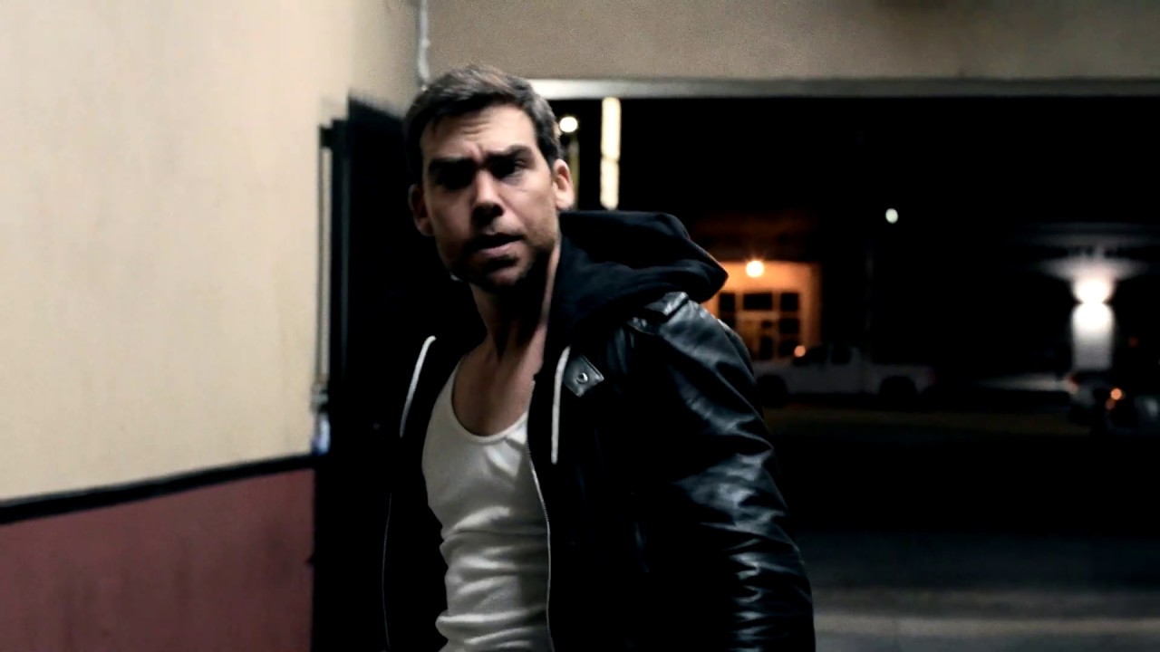 David Wachs in a leather jacket and white tank in a night alley, from the Alley Brawl short
