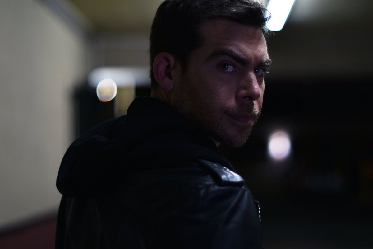 Dramatic night portrait of actor David Wachs in a leather jacket, looking over his shoulder