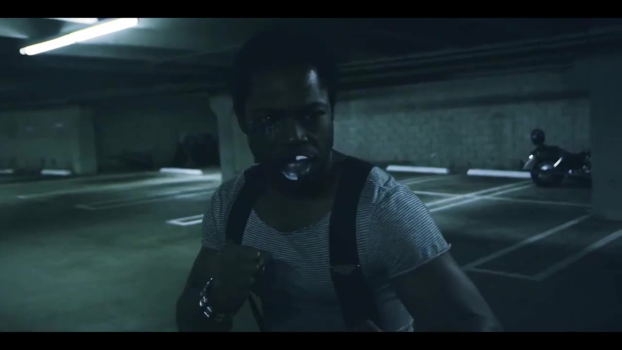 A fighter in a white tank top and suspenders squares up in a dark parking garage