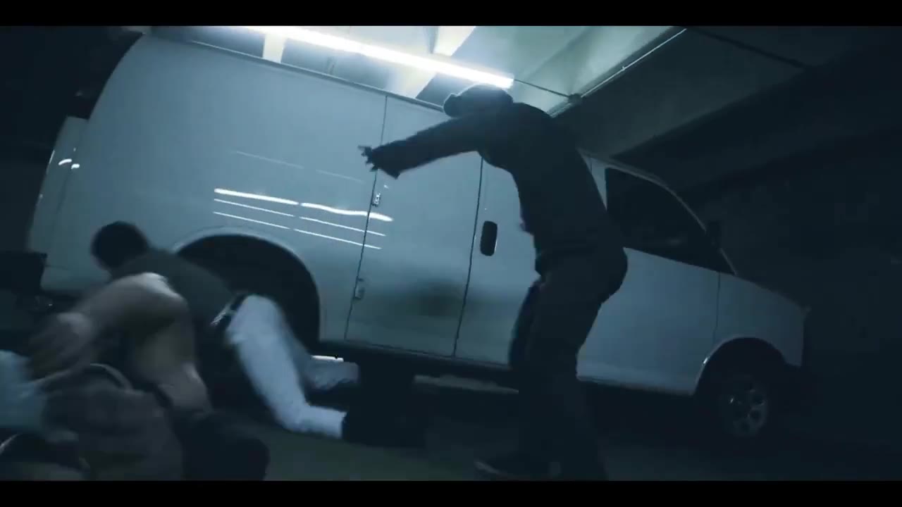 The hooded fighter throws a man into the side of a white van in the garage